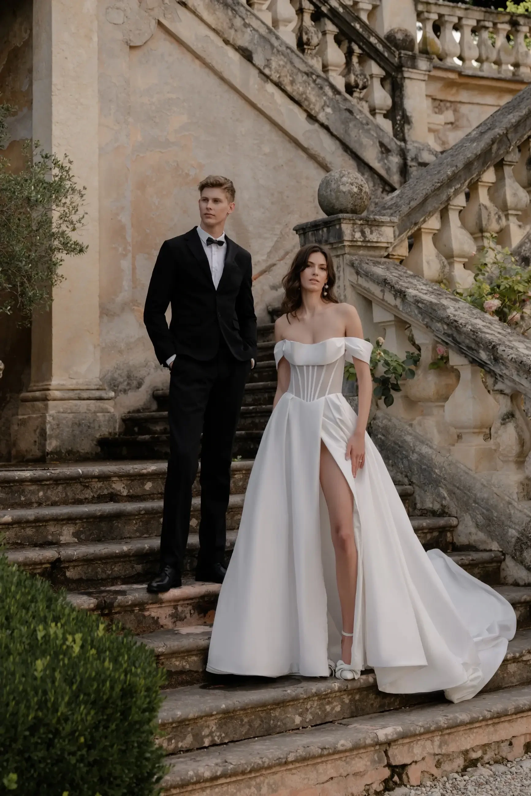model is wearing an off the shoulder a-line bridal gown with a corset bodice