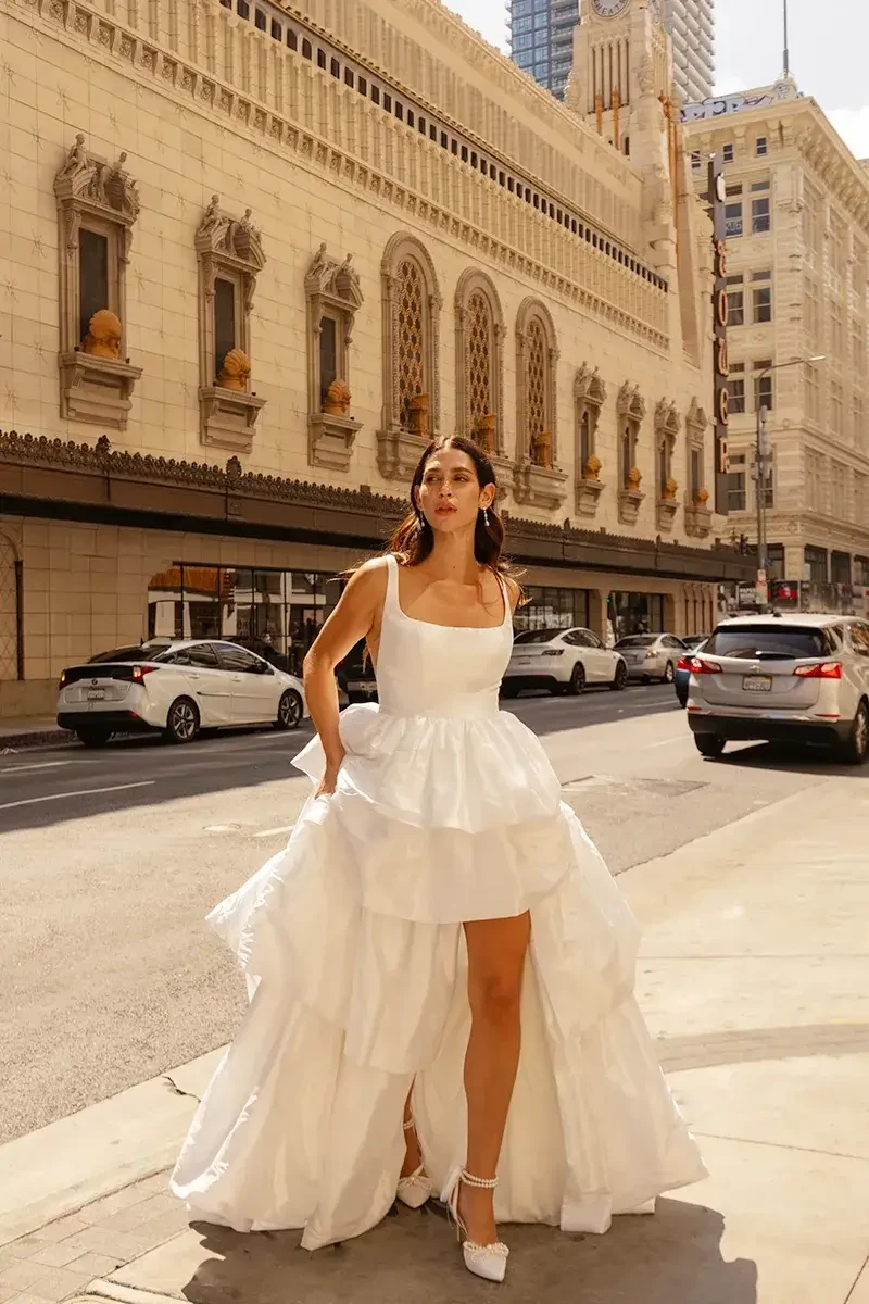 model is wearing a mini bridal dress with an overskirt