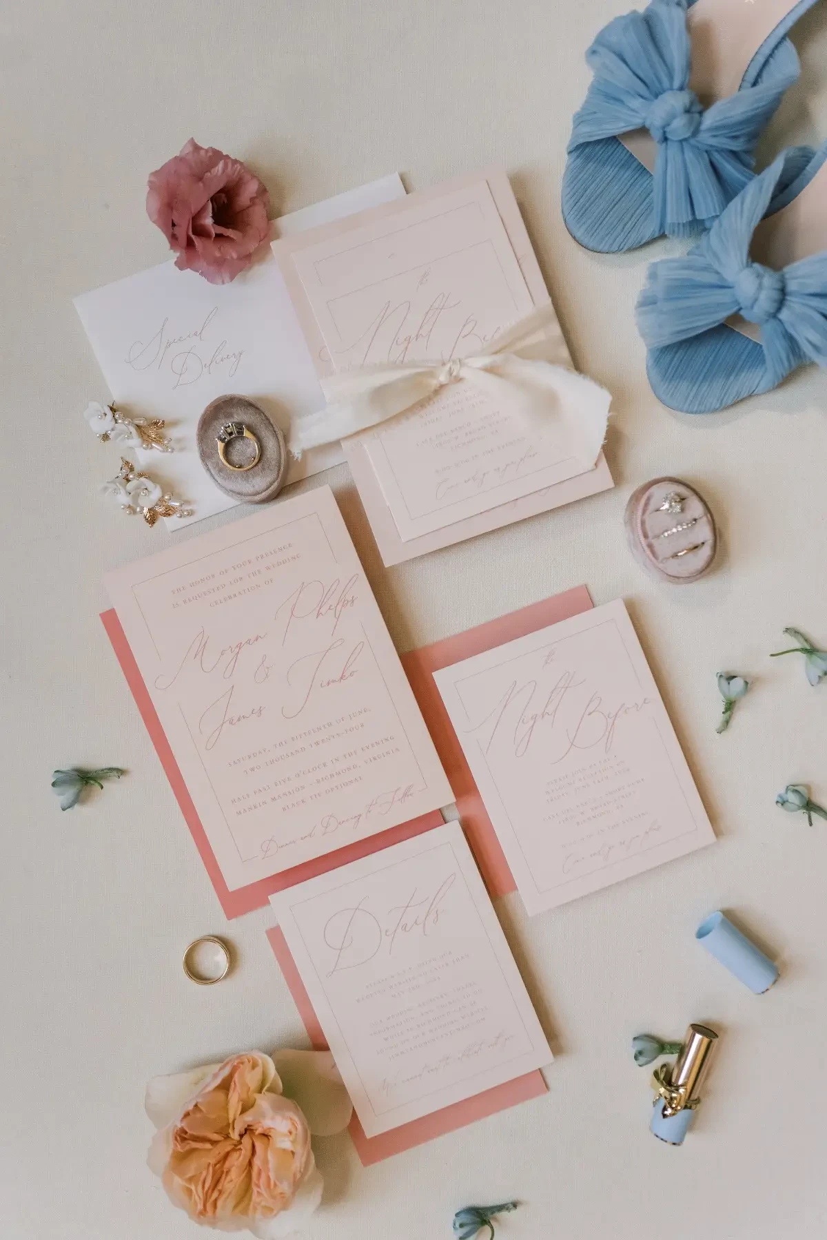 Image shows wedding day stationary in a dusty light pink with blue bridal heels off to the side and wedding rings
