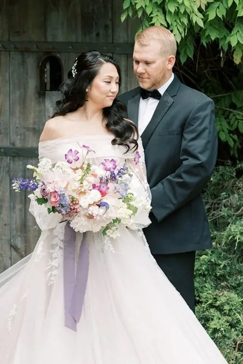 Сouple wearing a white gown and a black suit with a flowers